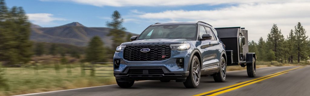 2026 Ford Explorer towing trailer on a scenic road.
