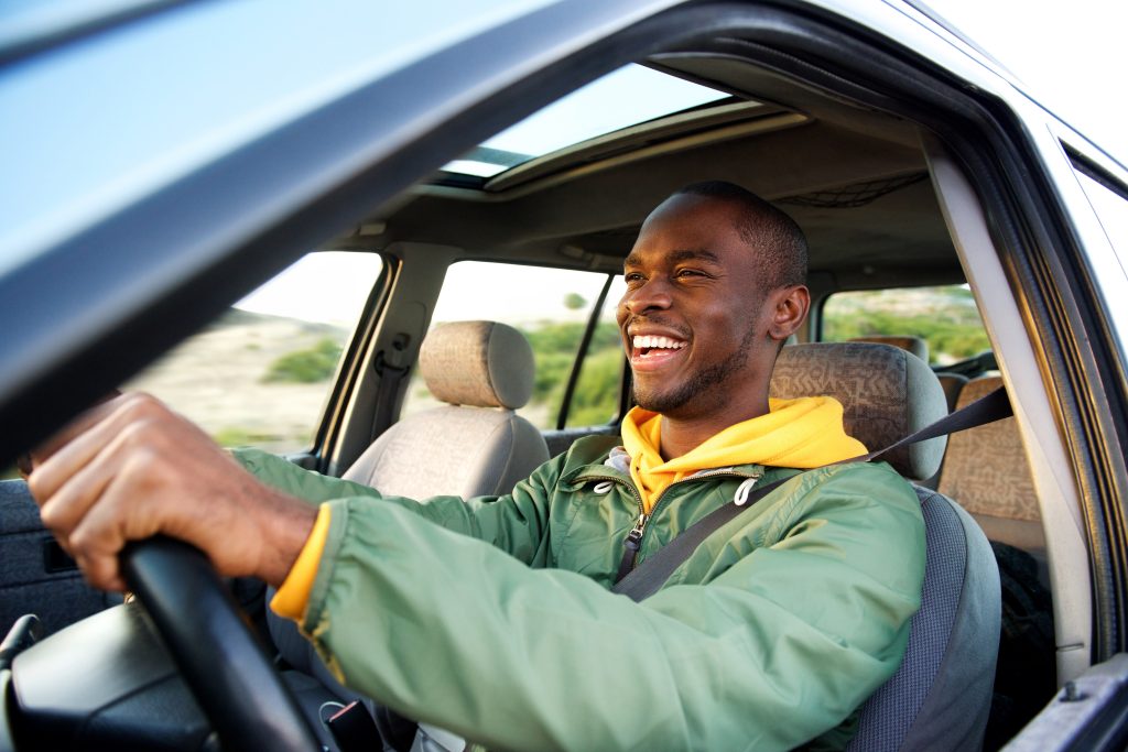 Smiling man driving a car with a seatbelt on.