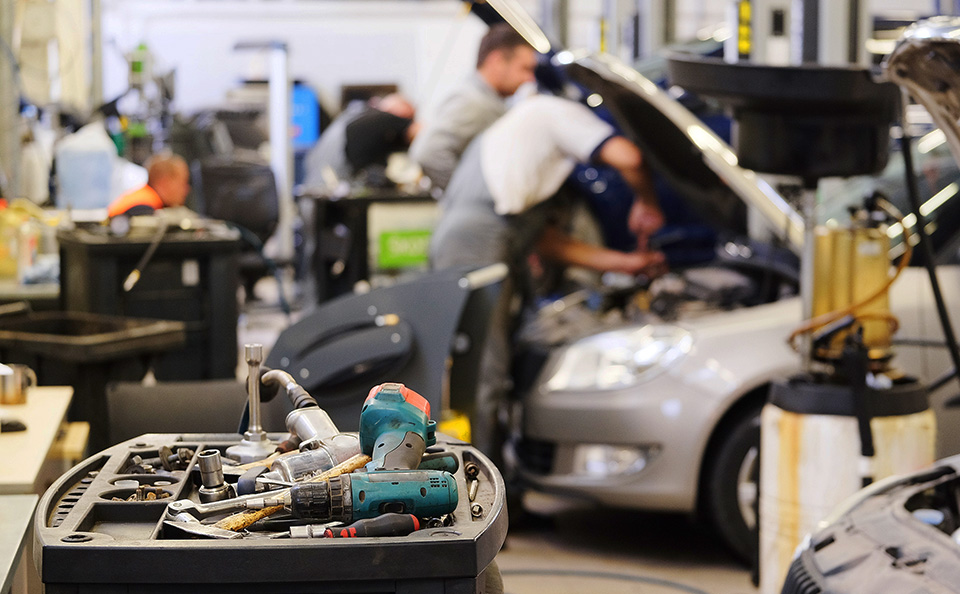 Mechanics working on a car in a garage with tools in foreground