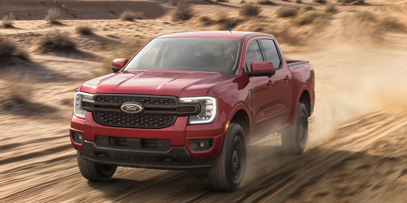 Red Ford Ranger driving on a dirt trail with dust behind it